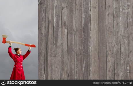 Woman with axe. Young woman in red coat with axe in hands