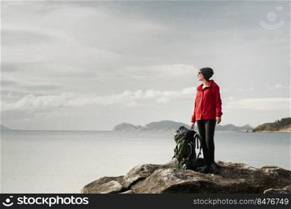 Woman with backoack enjoying the morning view of the coast