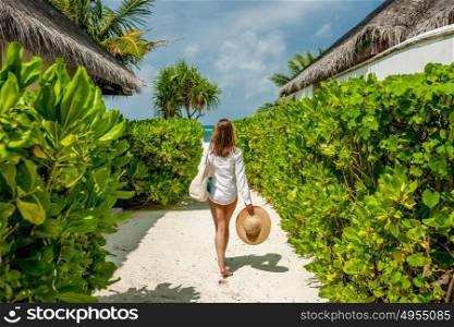 Woman with bag and sun hat going to the beach