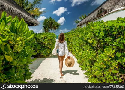 Woman with bag and sun hat going to the beach