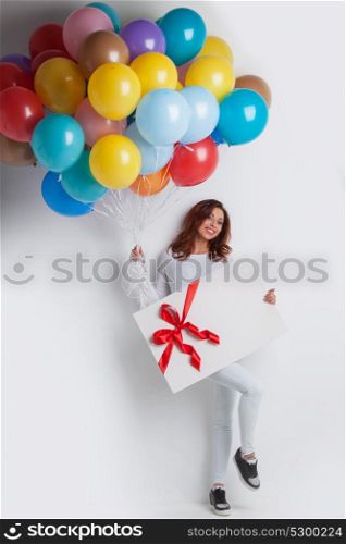 Woman with balloons and gift. Young smiling woman with balloons and big gift box