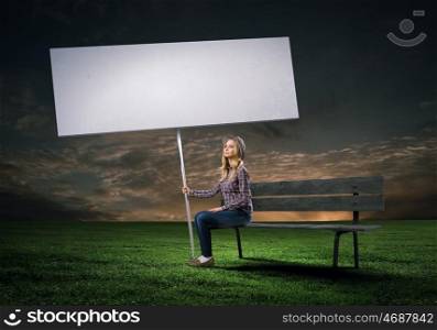 Woman with banner. Young girl in casual with white banner sitting on bench. Place for text