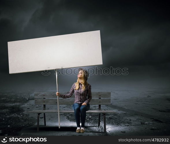 Woman with banner. Young girl in casual with white banner sitting on bench. Place for text