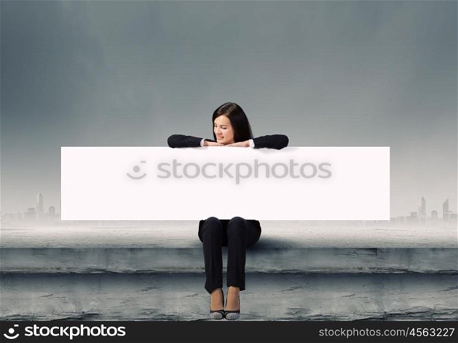 Woman with banner. Young woman sitting on top of building with blank banner