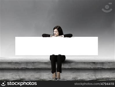 Woman with banner. Young woman sitting on top of building with blank banner