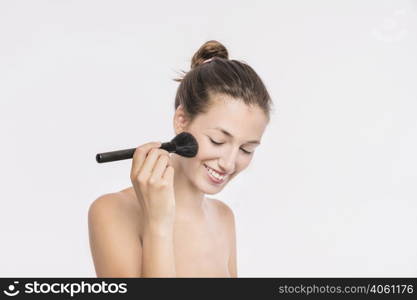 woman with bare shoulders using powder brush