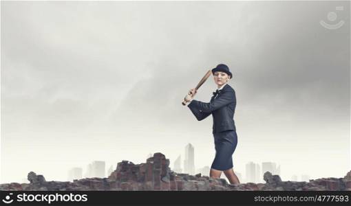 Woman with baseball bat. Young pretty woman in suit and hat crashing wall with baseball bat