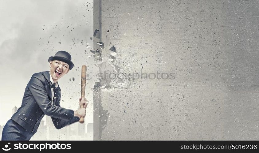 Woman with baseball bat. Young pretty woman in suit and hat crashing wall with baseball bat