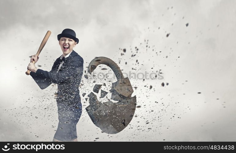 Woman with bat. Young emotional woman crashing lock with baseball bat