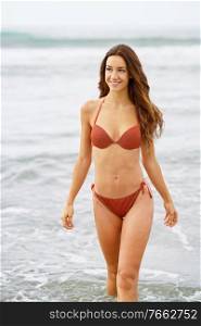 Woman with beautiful body enjoying her bath on the beach wearing red bikini. Woman with beautiful body enjoying her bath on the beach
