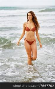 Woman with beautiful body enjoying her bath on the beach wearing red bikini. Woman with beautiful body enjoying her bath on the beach