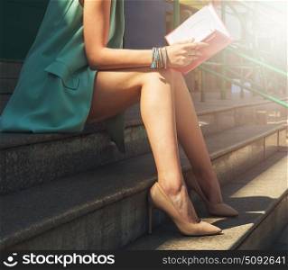 woman with beauty leg holding a book. Close up of woman with beauty leg holding a book on the street