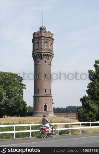 woman with bike looking at the big water tower in the dutch city Delden