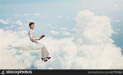 Woman with book. Adult woman in suit with old book in hand sitting on cloud