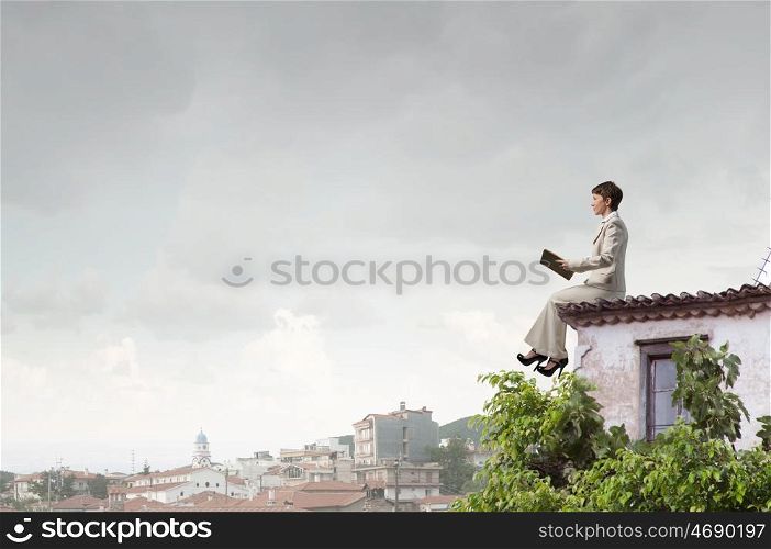 Woman with book. Adult woman in suit with old book in hand sitting on roof