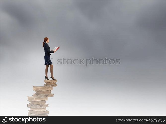 Woman with book. Young businesswoman on pile of old books with red book in hands