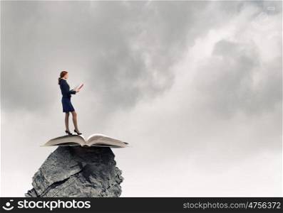 Woman with book. Young businesswoman on rock with red book in hands