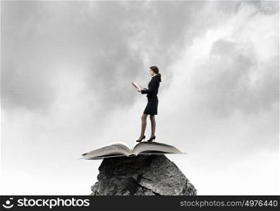 Woman with book. Young businesswoman on rock with red book in hands