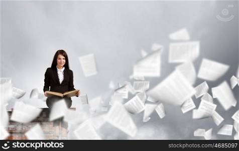 Woman with book. Young businesswoman sitting on building top with book in hands