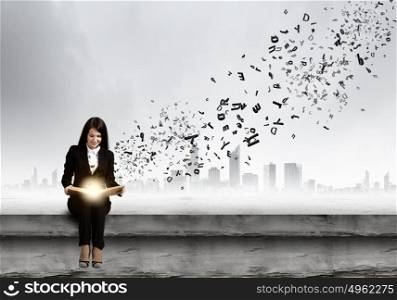 Woman with book. Young businesswoman sitting on building top with book in hands