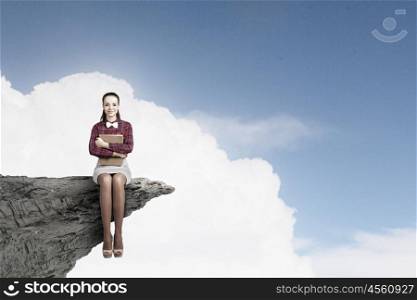 Woman with book. Young pretty woman on rock top with book in hands