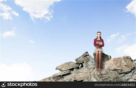 Woman with book. Young pretty woman on rock top with book in hands