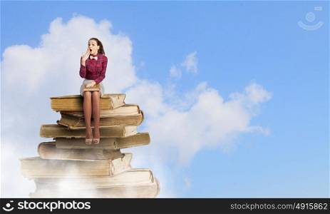 Woman with book. Young woman sitting on pile of books with book in hands