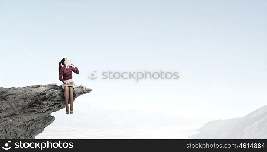 Woman with book. Young woman sitting on rock edge with book in hands