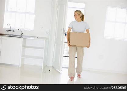 Woman with box moving into new home smiling