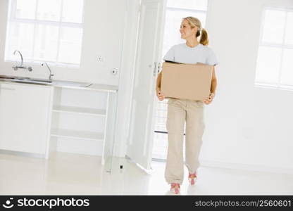 Woman with box moving into new home smiling