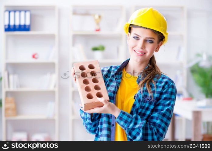 Woman with brick in construction concept
