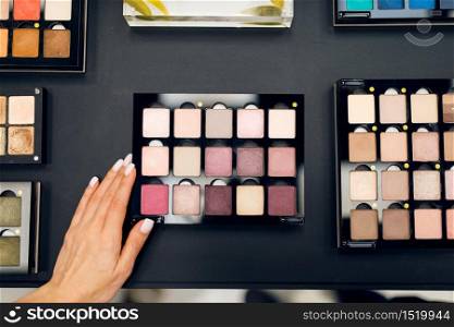 Woman with brush choosing shadows in cosmetics store. Buyer in luxury beauty shop salon, female customer in fashion market. Woman with brush choosing shadows, cosmetics store