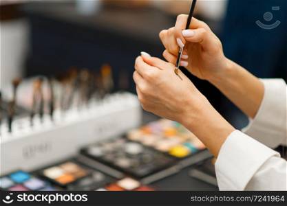 Woman with brush trying shadows tone in cosmetics store. Buyer in luxury beauty shop salon, female customer in fashion market. Woman with brush trying shadows tone in store