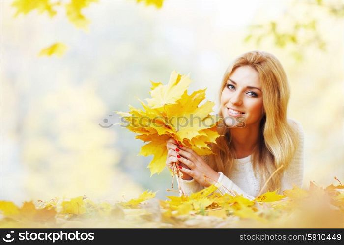Woman with bunch of maple leaves. Portrait of happy cute woman holding in hands bunch of dry maple leaves in autumn park