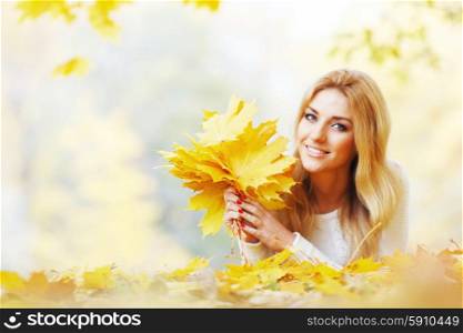 Woman with bunch of maple leaves. Portrait of happy cute woman holding in hands bunch of dry maple leaves in autumn park