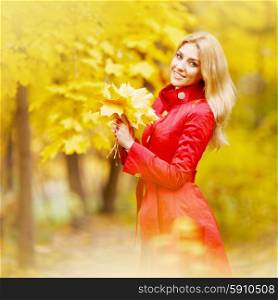 Woman with bunch of maple leaves. Portrait of happy woman holding in hands bunch of dry maple leaves in autumn park