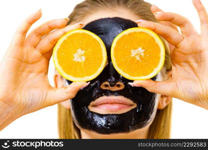 Woman with carbo detox black peel-off mask on face holding orange fruit. Teen girl taking care of oily skin, cleaning the pores. Beauty treatment. Skincare.. Girl black carbo mask on face holds orange fruit