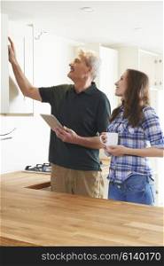 Woman With Carpenter Inspecting New Fitted Kitchen