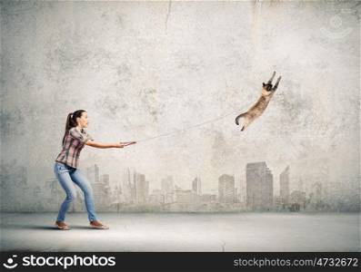 Woman with cat. Young woman in casual catching cat with rope