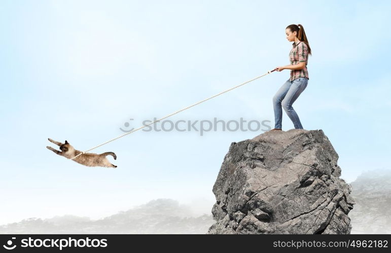 Woman with cat. Young woman in casual catching cat with rope