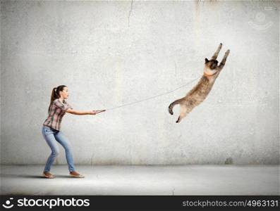 Woman with cat. Young woman in casual catching cat with rope