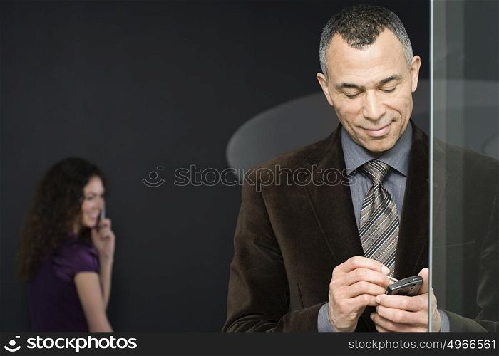 Woman with cellphone and man with handheld computer