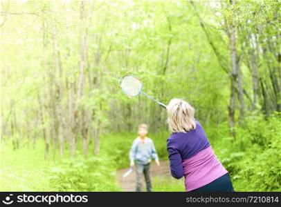 woman with child playing badminton in the woods