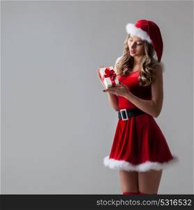 Woman with Christmas present. Excited surprised woman in red santa claus outfit holding Christmas present