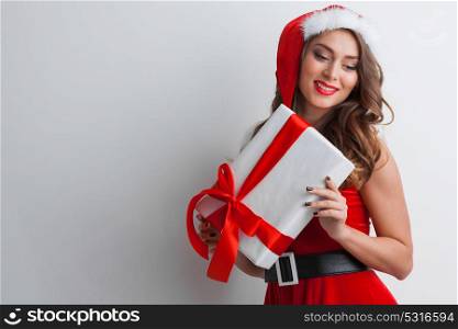 Woman with Christmas present. Excited surprised woman in red santa claus outfit holding Christmas present