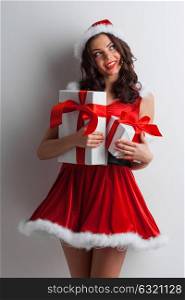 Woman with Christmas presents. Excited surprised woman in red santa claus outfit holding Christmas presents