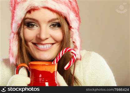 Woman with christmas sweets. Christmas food concept. Beauty happy girl in winter clothes holding beverage in red mug and cane.