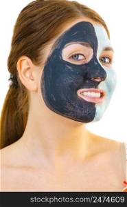 Woman with clay carbo black mask on half face and white mud on second half. Girl taking care of oily complexion. Beauty procedures. Skincare.. Girl with black white mud mask on face