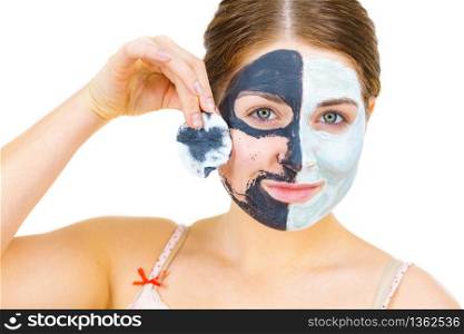 Woman with clay carbo black mask on one half face and white mud on second half. Girl removing cosmetic scrab with cotton swab. Female taking care of oily complexion. Skincare.. Girl remove black white mud mask from face