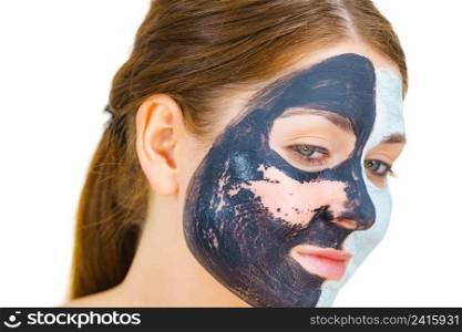 Woman with clay carbo black mask on one half face and white mud on second half. Girl removing cosmetic scrab. Female taking care of oily complexion. Skincare.. Girl remove black white mud mask from face